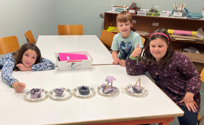 Three kids work on their craft
		projets