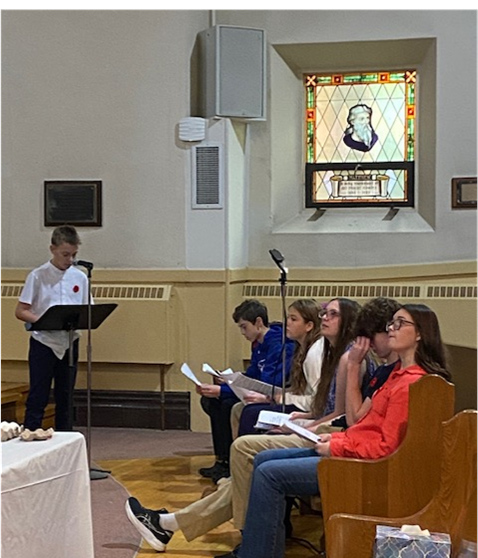 The youth sit in the
		front pew while one reads Scripture