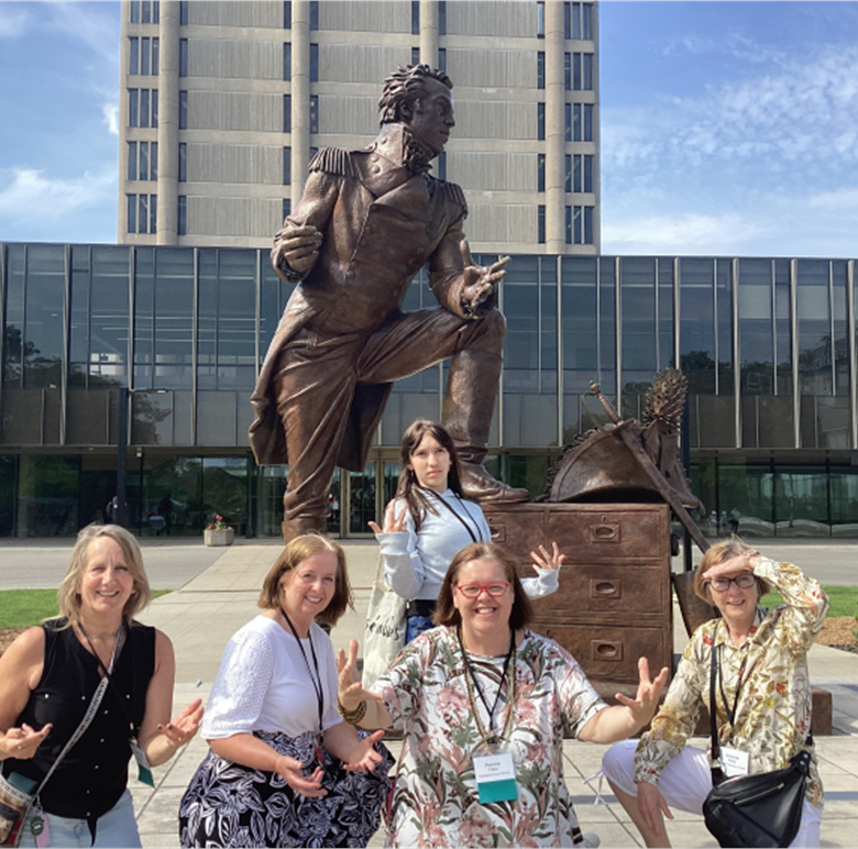 Posing with the
		statue